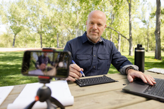 Cheerful Man Conducting Virtual Class With Phone In Park