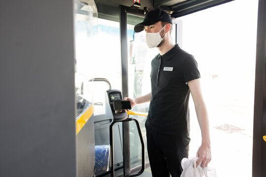 Teenage Male Worker In Face Mask Boarding Public Transit Bus