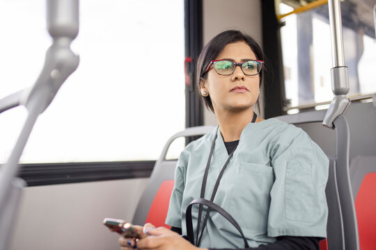 Female Nurse In Scrubs Using Smart Phone On Bus