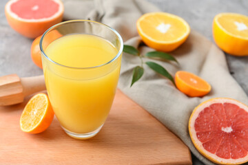 Glass with tasty citrus juice on grey background
