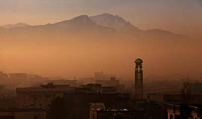 Sunrise scene over the city of Kabul in Afghanistan – Mosque tower and mountains – with buildings and infrastructure – misty weather