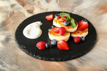 Slate plate with tasty cottage cheese pancakes and berries on grunge background