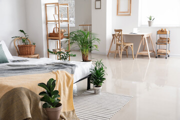 Interior of stylish bedroom with modern workplace and houseplants