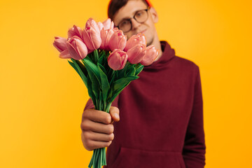 handsome man with a bouquet of flowers, a man in an orange hat and a red sweater holding flowers in his hands