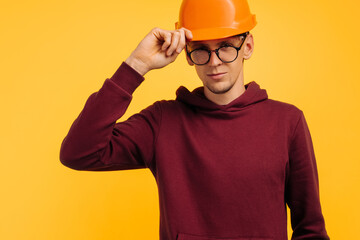 handsome man in construction helmet and glasses, young student builder, choice of profession for student