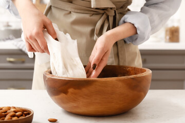 Woman preparing tasty almond milk on kitchen table, closeup