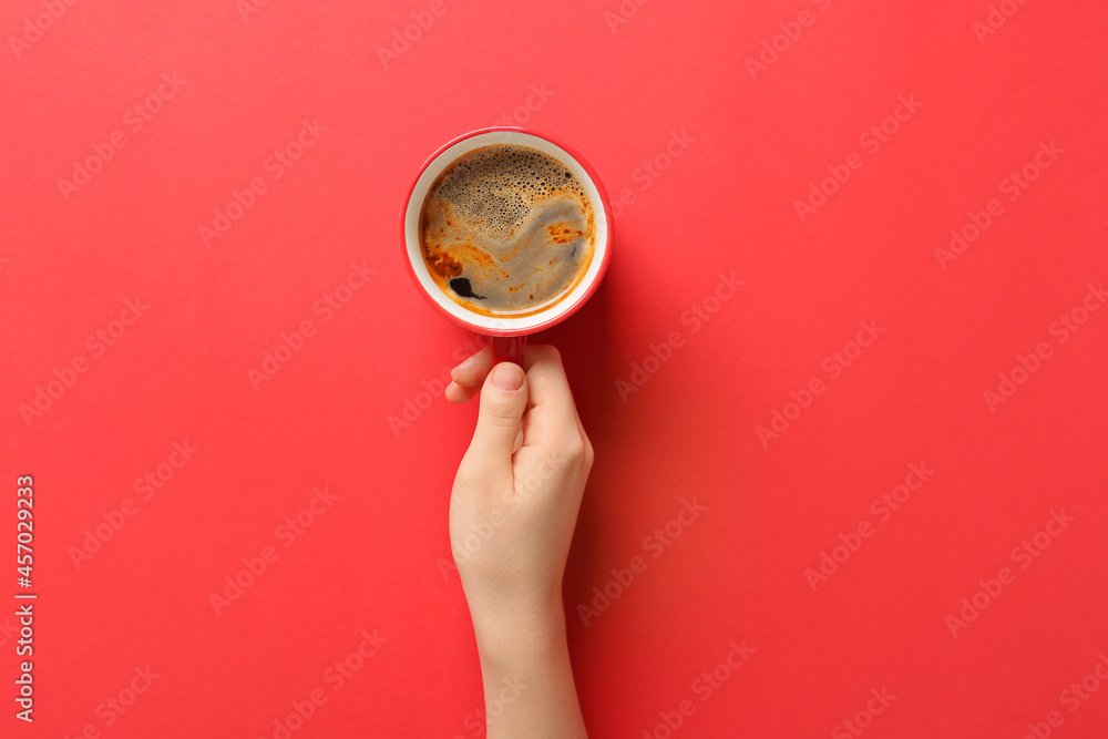 Wall mural female hand with cup of coffee on red background