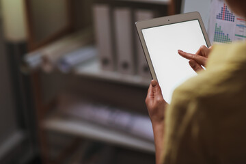 Young woman with tablet computer working in office late in evening, closeup