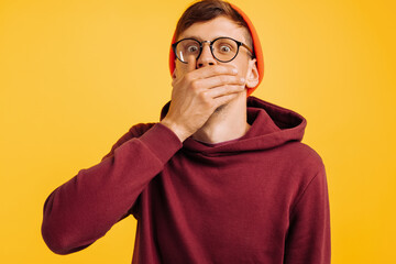 man covered his mouth with his hand, a frightened man, in an orange hat and red sweatshirt, and...