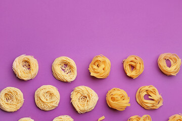 Different types of uncooked pasta on color background