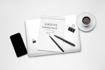 Stationery with text WORKPLACE HARASSMENT, cup of coffee and gadgets on white background