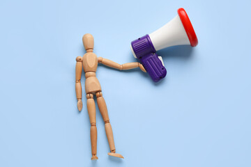 Wooden mannequin with toy megaphone on color background