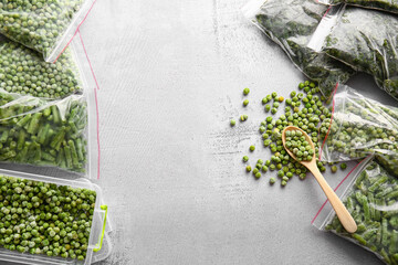 Plastic container and bags with different frozen vegetables on grey background