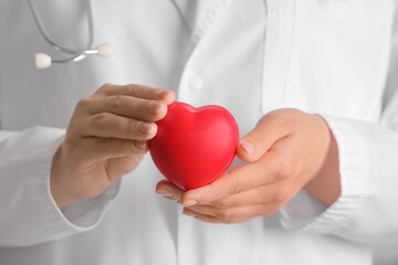 Female cardiologist holding red heart, closeup