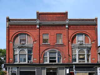 Facade of the type of ornate brick main street commercial building common in the 1800s, with stores on the ground floor and apartments above