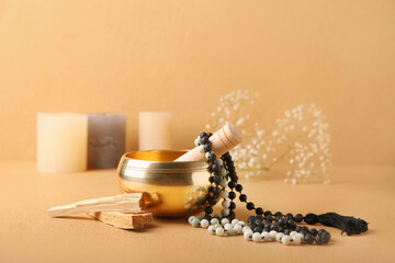 Tibetan singing bowl with beads and Palo Santo on color background