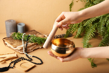 Hands with Tibetan singing bowl on color background