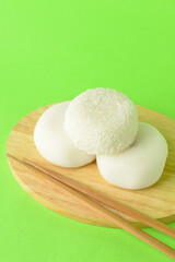 Board with tasty Japanese mochi and chopsticks on color background