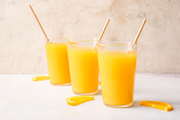 Glasses of tasty orange juice on light background