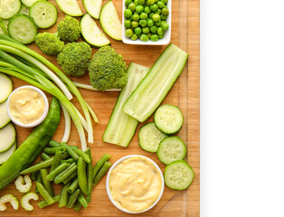 Board with different green vegetables on white background
