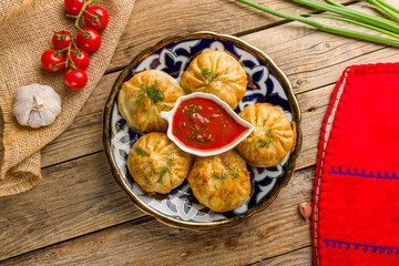 fried manty uzbek cuisine with tomato sauce on wooden background, top view food