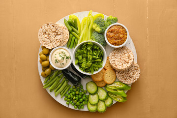 Wooden board with different green vegetables and bowls with sauce on color background