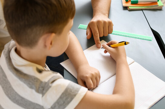 Little boy with his father doing lessons at home, closeup