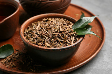Obraz premium Tray with dry hojicha green tea on grey background