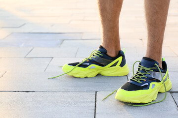 Sporty young man with undone shoe laces outdoors