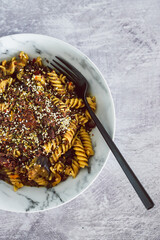 vegan pesto fusilli pasta with black beans and mediterranean veggies topped ith mixed seeds,...