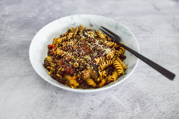 vegan pesto fusilli pasta with black beans and mediterranean veggies topped ith mixed seeds, healthy plant-based recipes