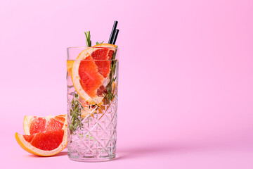 Glass of cold gin tonic and grapefruit slices on color background
