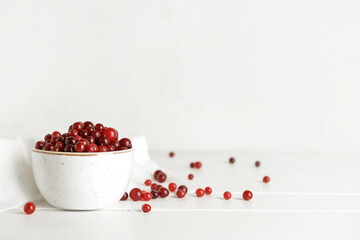 Bowl with healthy cranberry on light wooden background