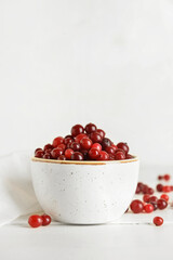 Bowl with healthy cranberry on light wooden background