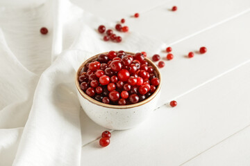 Bowl with healthy cranberry on light wooden background