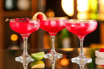 Glasses of tasty cosmopolitan cocktail with berries and fruits on table in bar