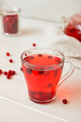 Cup of tasty tea with cranberry on light wooden background