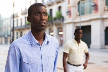 Portrait of African American man in light shirt on background of summer cityscape