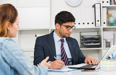 Successful businessman in glasses talking to female colleague in office
