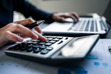 Close up of businesswomen or accountant using a calculator calculates and laptop computer while...