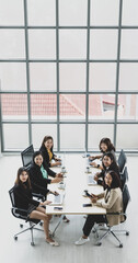 High view of six executives businesswomen sitting on each chairs using laptops and tablets on wooden conference table in meeting room in office. Concept for business meeting