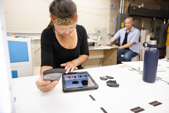 Female maker with digital tablet at workbench