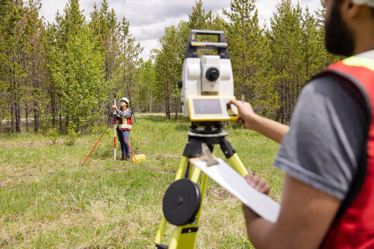 Surveyor using equipment to measure field with trees