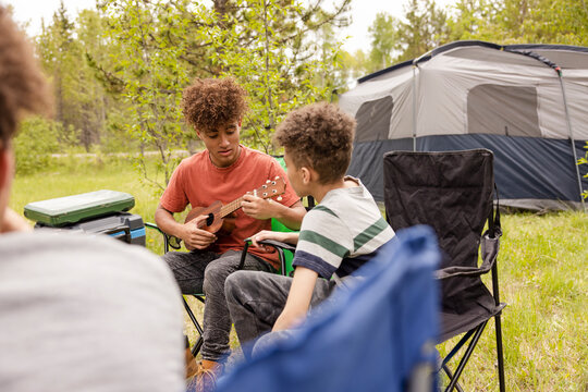 Boy playing ukulele on campsite