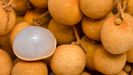 A pile of longan and longan fruit with white flesh on background.