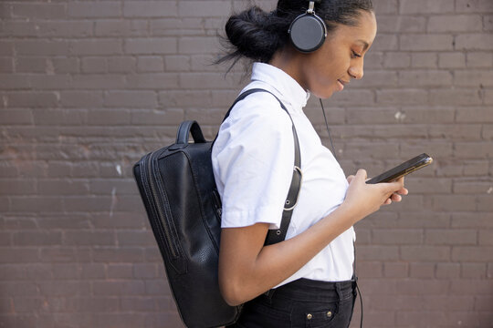Young woman with backpack and headphones using smart phone