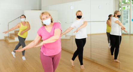 Fototapeta na wymiar People in protective masks learning swing steps at dance class