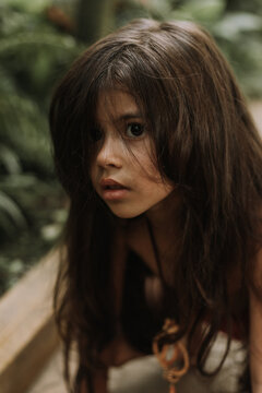Closeup portrait mowgli indian little girl in a loincloth hides hiding in tropics green forest background. High quality photo