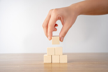 Hand putting and stacking blank wooden cubes on table with copy space.