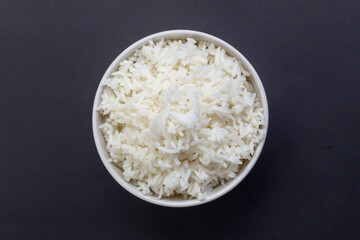 cooked rice in a white bowl on a black background.